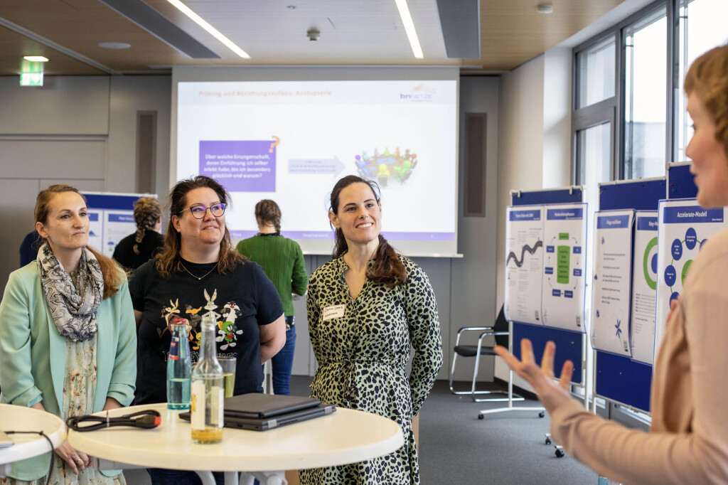 Präsentationstraining mit Fokus auf Auftritt und Wirkung: Teilnehmende im Austausch mit Trainerin vor Visualisierungen und Beamer-Präsentation.