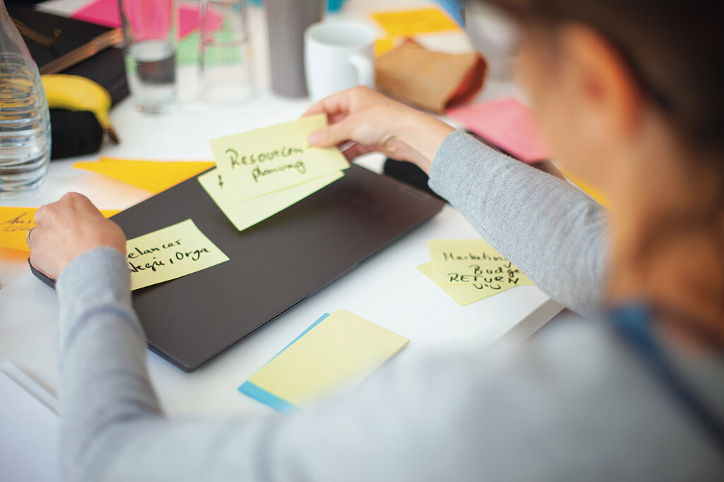 Person arbeitet mit Haftnotizen zu Ressourcenplanung und Strategie – Symbol für agiles Arbeiten.“.